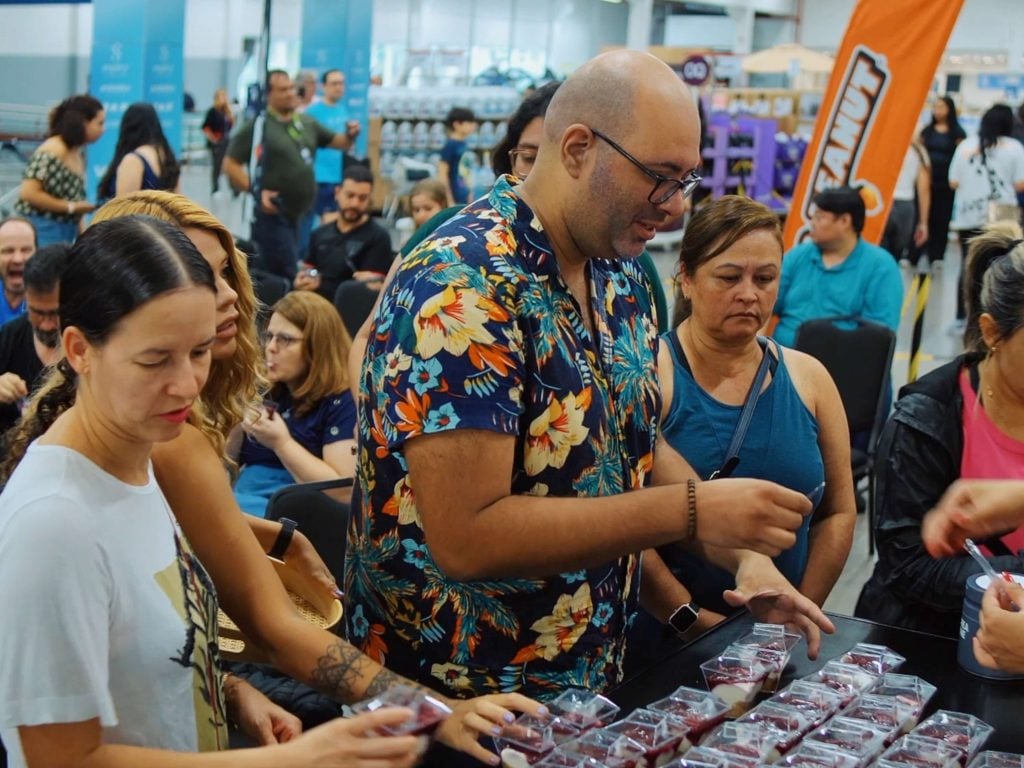 Clientes reunidos em bancada de degustação experimentando sobremesas em evento no Sam’s Club