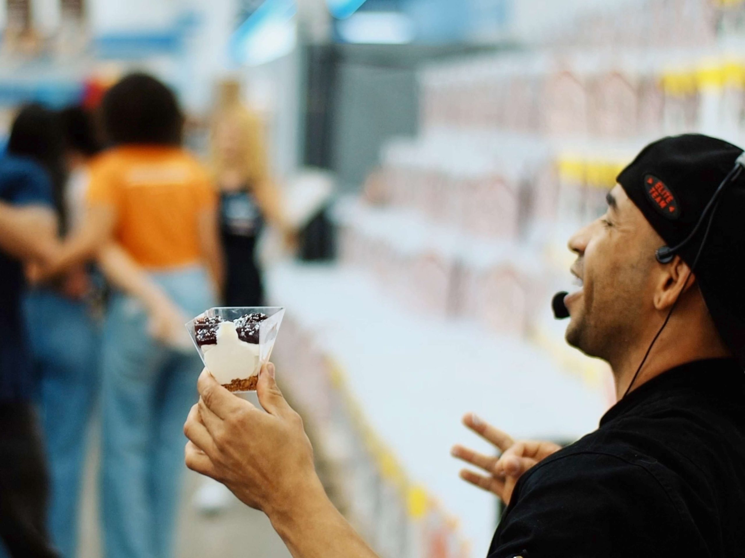 Chef com microfone apresenta sobremesa em taça durante demonstração gastronômica no Sam’s Club